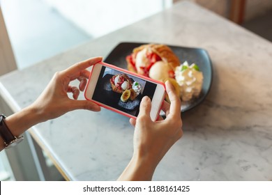 Sharing photo on the social media. Woman taking a photo of the desserts by her smart phone. Social media lifestyle concept.