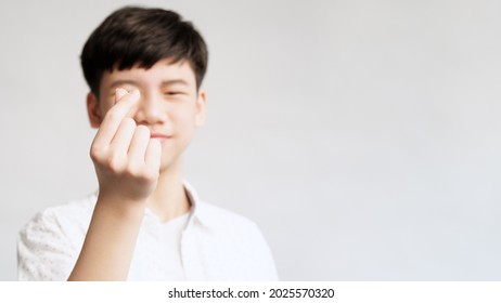 Sharing And Support Concept. Portrait Of A Smart Asian Teenager Boy In White Casual Doing Mini Heart Hand Gesture And Smiling To Camera. Teen Health, Word Heart Day, Donation, Love, Mental, Youth.