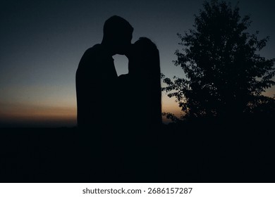 Sharing a tender memory. The simple act of a kiss, with a focus on a treasured item, beautifully conveys the depth of their connection at dusk.