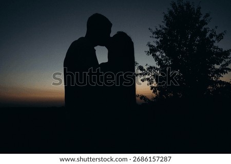 Sharing a tender memory. The simple act of a kiss, with a focus on a treasured item, beautifully conveys the depth of their connection at dusk.