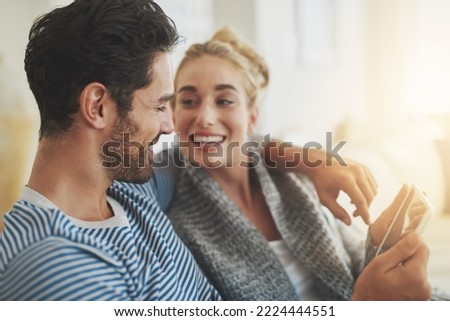 Sharing the things they love with the convenience of technology. Shot of a young couple using a digital tablet on their sofa at home.