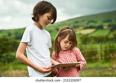 Sharing The Wonders Of The Digital World. Shot Of Two Little Siblings Using A Digital Tablet Together Outdoors.