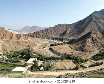 Sharjah, United Arab Emirates - March 23, 2022: Panoramic view of Wadi Washi desert oasis in the Hajar Mountains in Khorfakkan, seen from ancient Najd Al Maqsar fortress and Emirati heritage village.