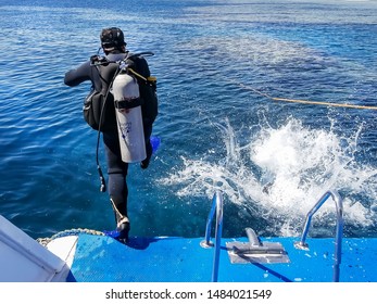 Sharm El Sheikh, Egypt - 29 Jule 2019:Scuba Diver In His Gear On A Dive Boat Standing Ready To Enter The Water From The Back Of The Boat, High Angle View With The Wake Of The Moving Boat Behind