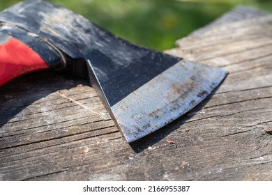 A sharp ax with an ergonomic rubberized handle on a wooden background. The ax is intended for rough, rough processing of wood. Has a forged heat treated carbon steel wedge.