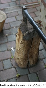 Sharp Axe Embedded In Weathered Log, Showing Worn Wooden Block On Cobblestone Patio, Chipped Metal Head,