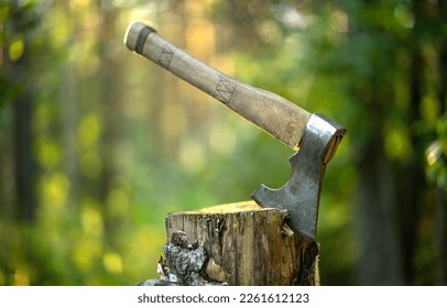 Un hacha afilada con una manecilla de madera se adentra en un trozo de madera en el bosque. Una herramienta de leñador. Madera de cortar. Para derribar un árbol en el bosque.
