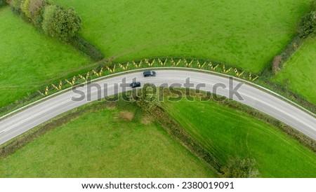 Sharp bend in a road with Chevron warning signs. Aerial view from above. Road safety.  Two black cars pass each other on the bend. Road safety. 