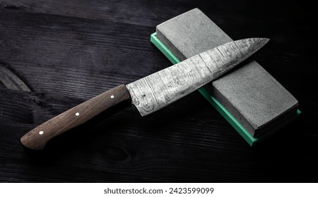 Sharp Chef's Kitchen Knife And Sharpening Stone Lie On Dark Table