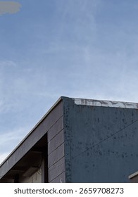 A sharp corner of a modern building with minimalistic design, set against a soft blue sky. Clean and geometric urban aesthetic.