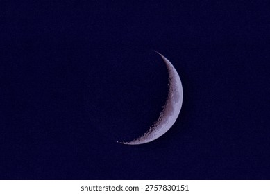 Sharp crescent moon with visible surface details and craters set against a deep blue night sky, ideal for astronomy and space themes.
