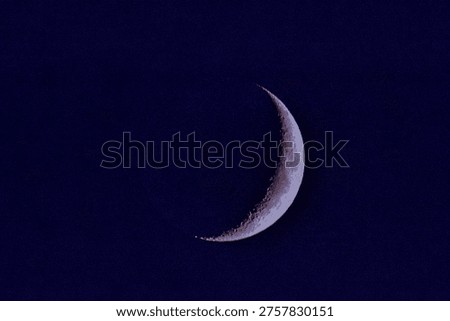 Sharp crescent moon with visible surface details and craters set against a deep blue night sky, ideal for astronomy and space themes.