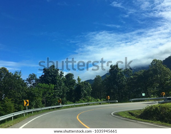 Sharp curve road, along the mountain road, blue sky,\
white clouds 