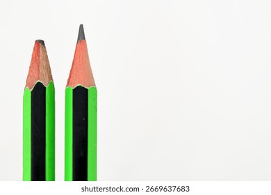 Sharp and Dull Pencils. A close-up of two green and black pencils against a plain white background, highlighting the contrast between a freshly sharpened and a dull one.