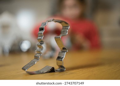 A sharp focus on a metal baking mold with a young child wearing red clothes blurred out in the background, creating a warm family atmosphere.