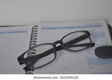 A sharp, focused image capturing the essence of productivity�glasses resting on a monthly planner, perfect for themes of planning, vision, and organization.