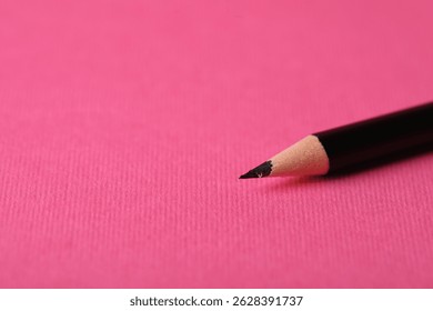 Sharp graphite pencil on pink background, closeup. Space for text