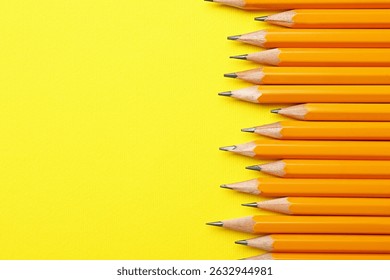 Sharp graphite pencils on yellow background, flat lay. Space for text