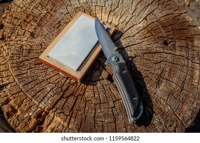 Sharp knife and grindstone on a wooden background