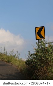 Sharp left turn traffic sign on the side of a mountain road.