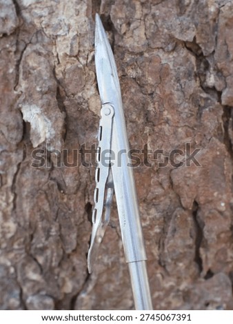 Sharp metal spearhead tip with barb attachment.