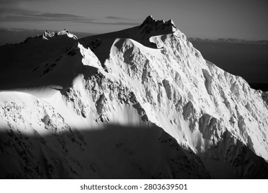A sharp mountain peak covered in snow against a dark sky, dramatic and cold.