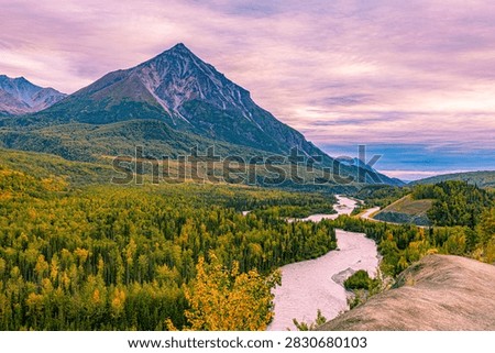 A sharp peak towers over the Matanuska River and autumn forest along Alaska's Glenn Highway.