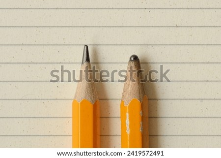 Sharp pencil and dull pencil on lined notebook paper - Concept of success, innovation and creativity