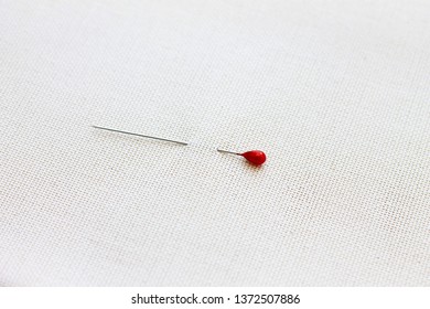 Sharp Pin With A Red Head Pinned To A Light Fabric Concept Of Needlework, Sewing And Creativity