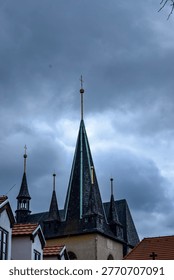 The sharp, pointed roofs of ancient architecture stand out against a moody, grey cloudscape, evoking a sense of history and solemnity