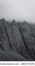 the sharp, rocky limestone peaks of Tre Cime di Lavaredo in the Italian Dolomites, partially obscured by dense clouds.