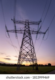 Sharp Silhouette Of Electricity Tower Construction And Power Lines Against A Colourful Orange And Magenta Blue Purple Sunset Sky