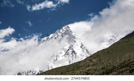 A sharp snowy mountain peak piercing through clouds