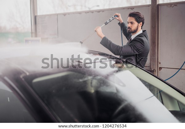 Sharp-dressed man\
washing his car in car\
washing.