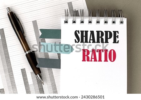 SHARPE RATIO text on a notebook with pen, calculator and chart on a grey background
