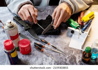 Sharpen the serrated knife. Sharpen a knife with a saw. File for a knife. Tool in hand. Oil, grindstones and tools on the table. View from above.