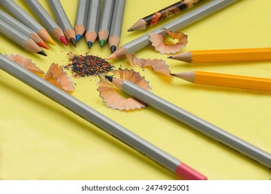 Sharpened pencil, eraser, compass and paper clips on a yellow background