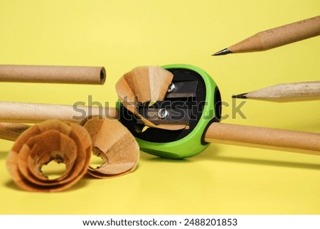 sharpening graphite pencils with a sharpener on a yellow background