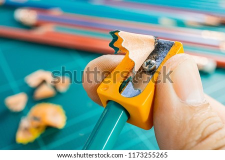 Sharpening green pencil with orange sharpener, marco picture