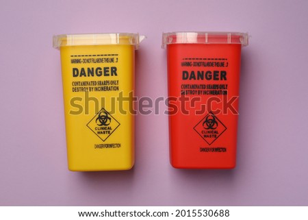Sharps containers for used syringe on violet background, flat lay
