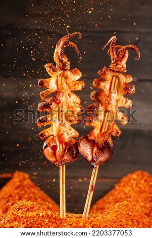 Shashlik. Kebab. Grilled barbecue squid with spices on black background