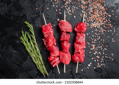 Shashlik raw beef veal shish kebab, Meat with herbs on Skewers. Black background. Top view - Shutterstock ID 2102508844