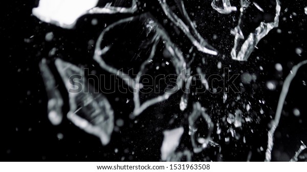 Shattered and broken glass\
shards flying through the air after crush broken window on a black\
background