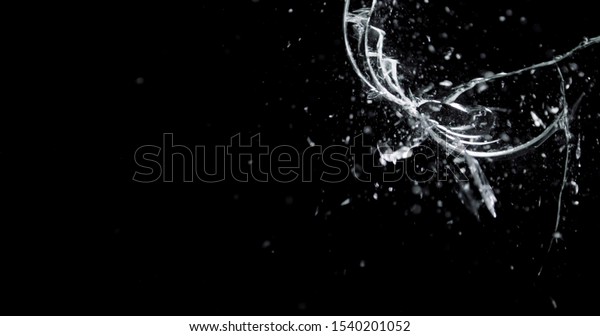 Shattered and broken glass\
shards flying through the air after crush broken window on a black\
background