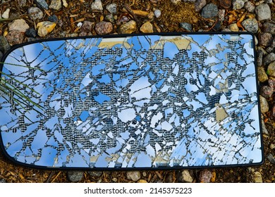 Shattered vehicle mirror sitting on gravel surface . symbolizing someone or something in trouble or disarray.