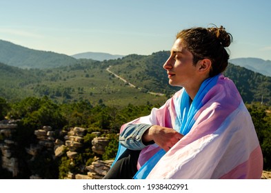 Shaved Long Hair  Young Man Sitting at Nature Breathing Deep with Closed Eyes Wrapped with Transgender LGTB Flag