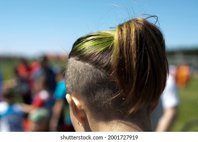 Shaved Whiskey And Green Hair. Modern Female Hairstyle. Hair Is Pulled Back In A Ponytail. Green Hair Dye. Partially Shaved Head. The Man Is Filmed From The Back Of His Head.