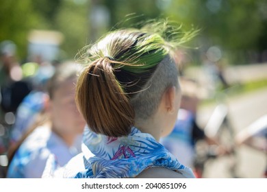 Shaved Whiskey And Green Hair. Modern Female Hairstyle. Hair Is Pulled Back In A Ponytail. Green Hair Dye. Partially Shaved Head. The Man Is Filmed From The Back Of His Head.