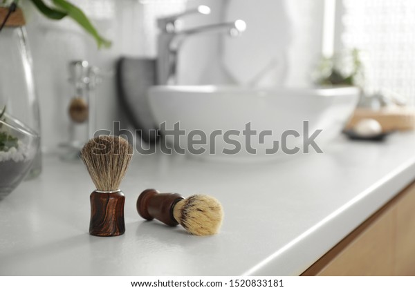 Shaving brushes\
on light countertop in\
bathroom