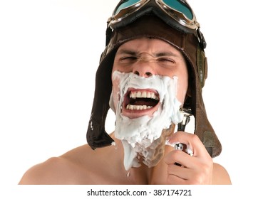 Shaving Portrait Screaming From Pain Of Man With Shaving Foam On His Face In Flight Helmet And Flying Goggles